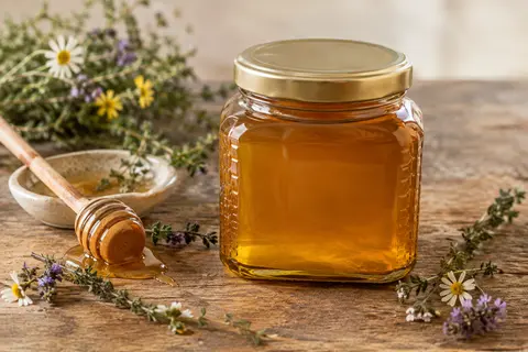 Boîte métallique de miel grec avec une coupelle de miel, du thym, des fleurs sauvages et du sapin