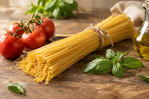 Spaghetti longs servis avec une sauce tomate, du basilic et un filet d’huile d’olive sur une table en bois.