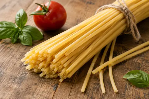 Spaghettoni épais servis avec une sauce tomate au basilic sur une table en bois