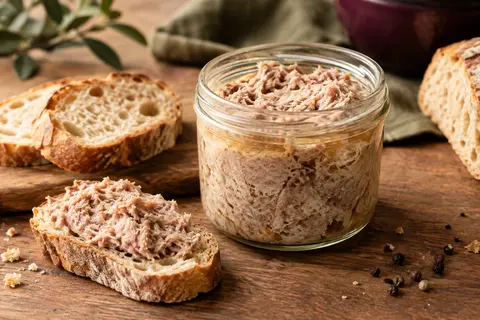 Rillettes de porc du Mans servies dans un plat avec du pain de campagne sur une table en bois