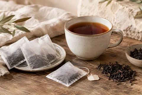 Tasse de thé noir décaféiné accompagnée de sachets sur une table en bois patiné